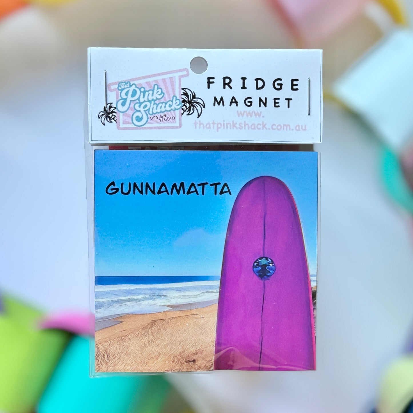 A fridge magnet with a pink surfboard overlooking the surf at gunnamatta beach Mornington peninsula in packaging