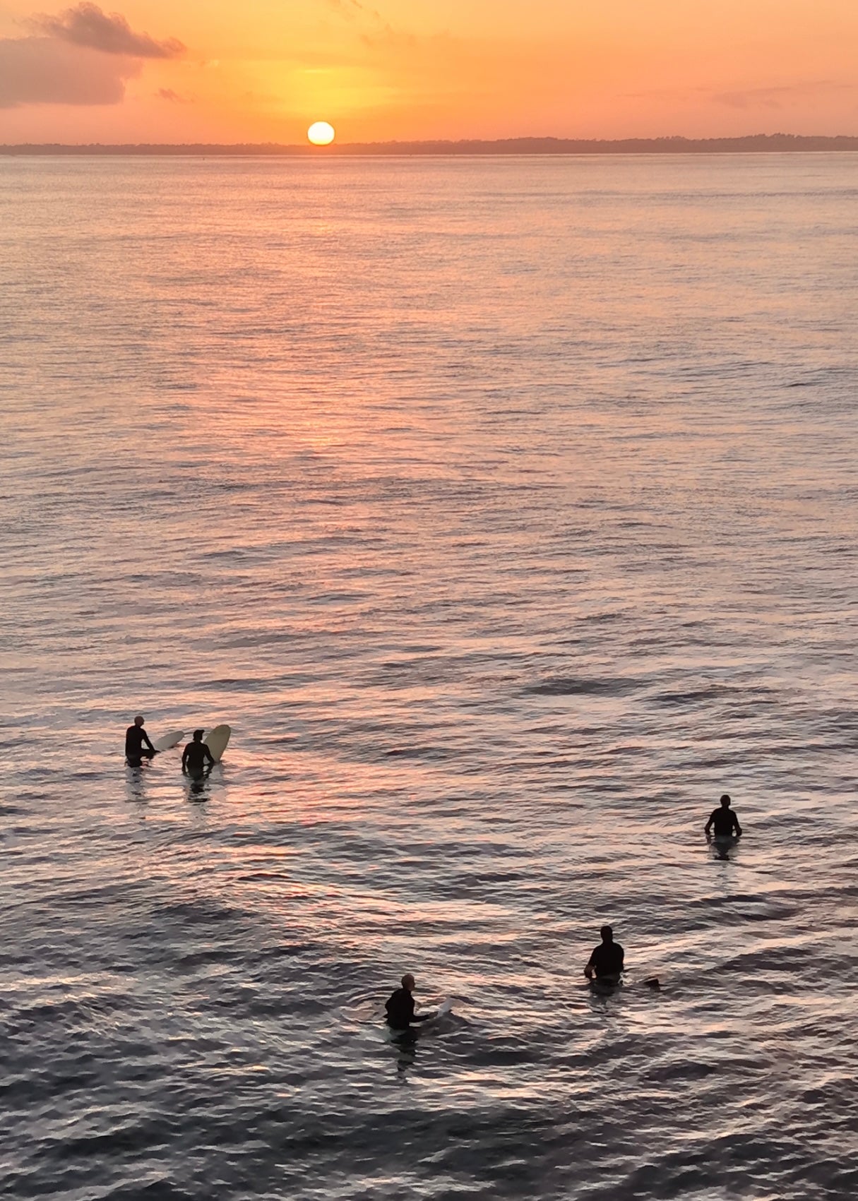 5 surfers waiting for a set as the sunrises over the horizon