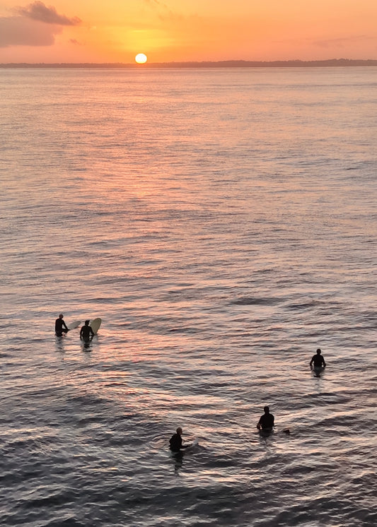5 surfers waiting for a set as the sunrises over the horizon