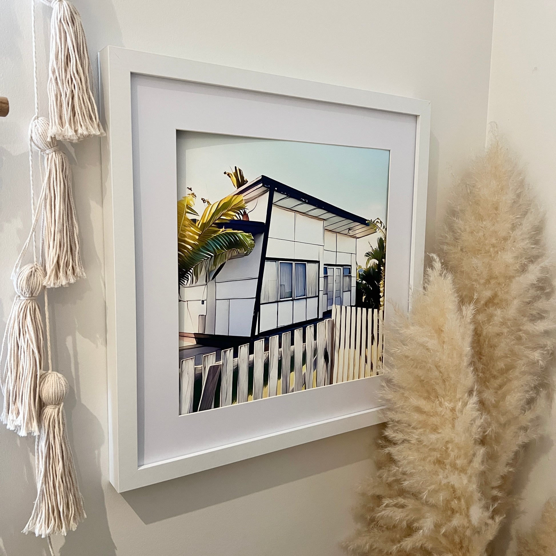 Retro white fibro beach shack with a skillion roof and a timber slat fence print In a white mat with a white frame