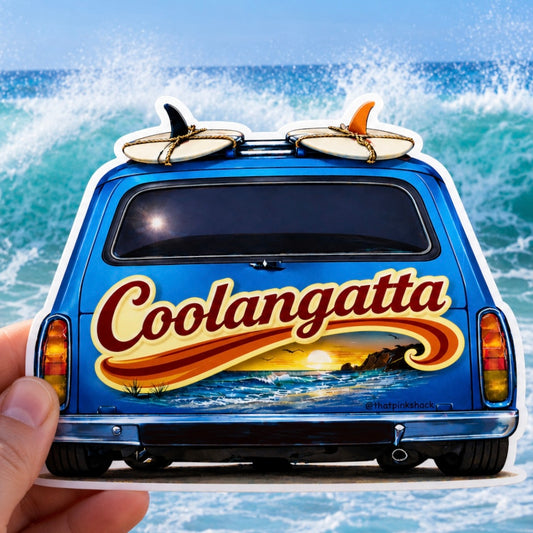 A die-cut sticker of a blue holden panel van with surfboards on top and the word 'Coolangatta' in large red lettering, held by a hand against a background of ocean waves.