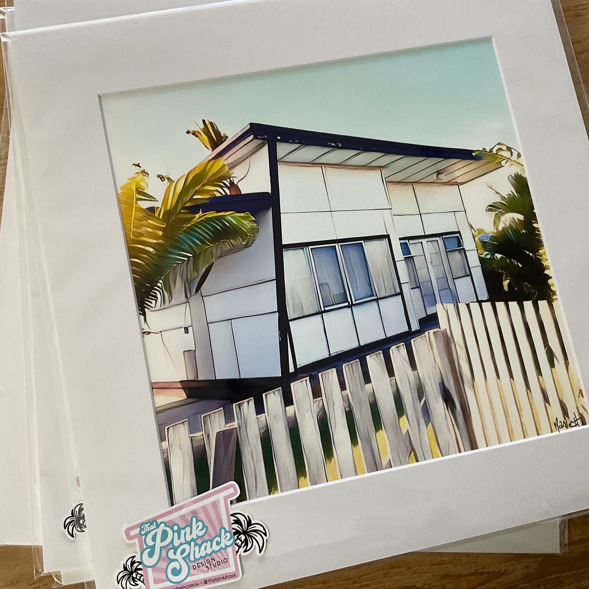 Retro white fibro beach shack with a skillion roof and a timber slat fence print In a white mat and a poly bag