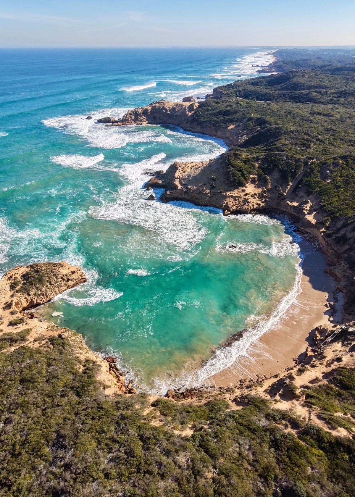 Aerial drone photograph of Diamond Bay, Sorrento, showing turquoise ocean, sandy beach, rugged cliffs and the Mornington Peninsula coastline.
