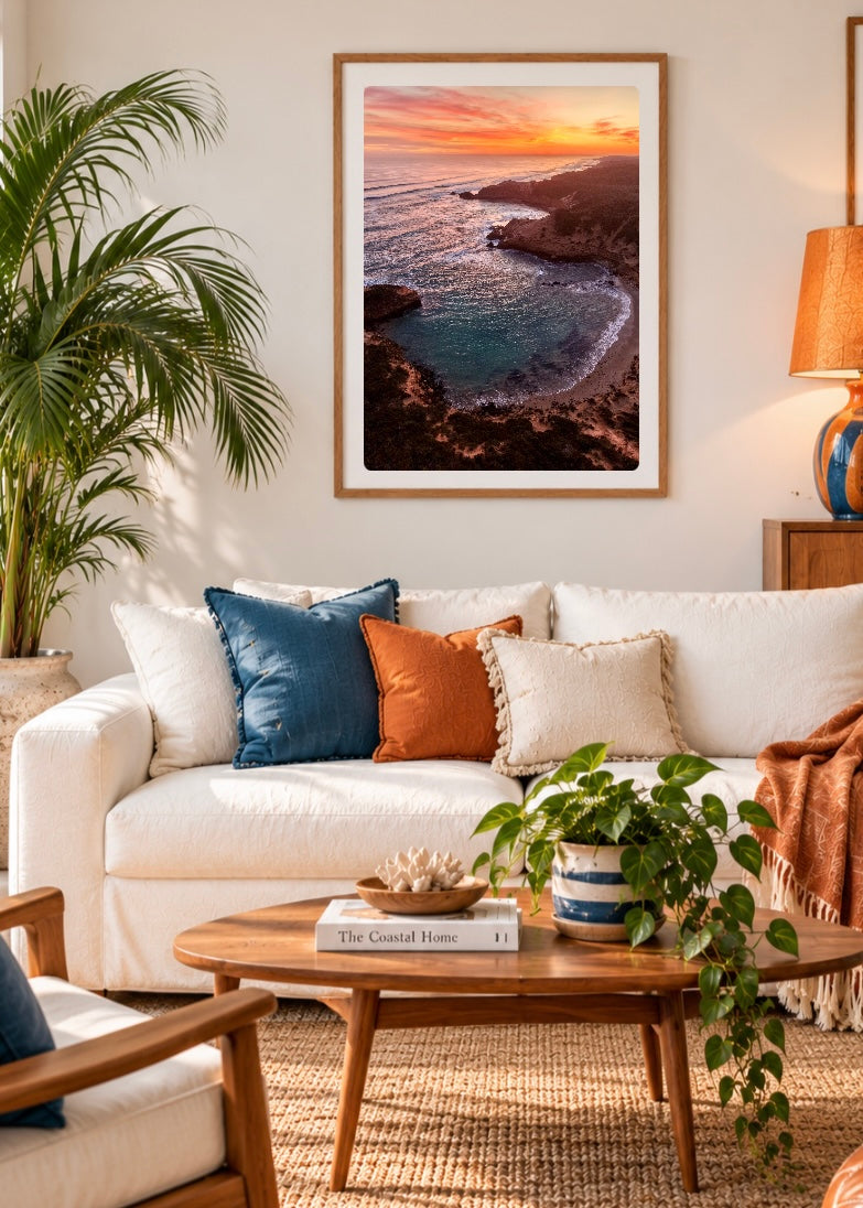 Aerial drone photograph of Diamond Bay, Sorrento at sunset showing turquoise ocean, sandy beach, rugged cliffs and the Mornington Peninsula coastline framed in a lounge room setting 