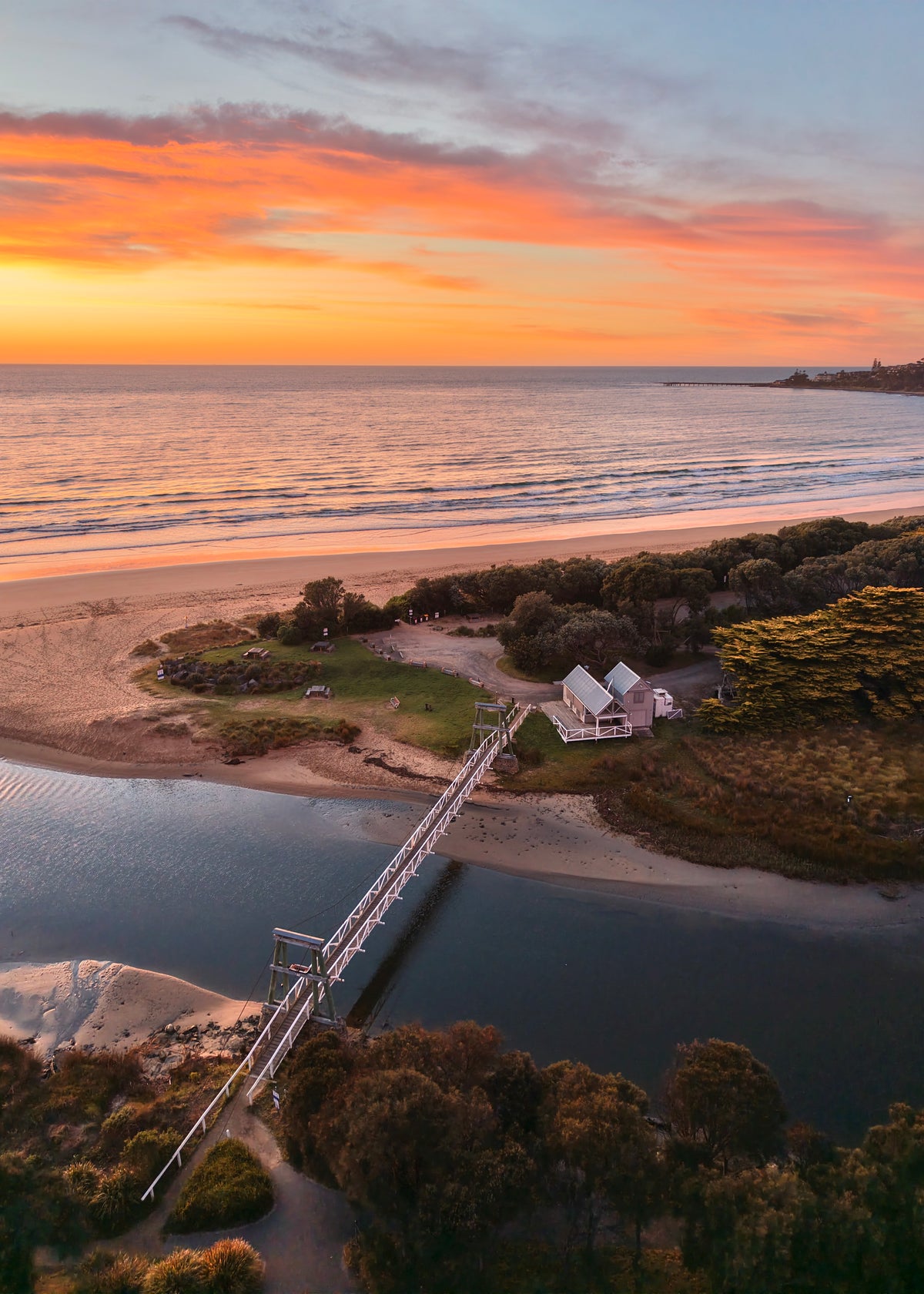 Colourful orange and yellow sunrise over the ocean from Erskine River in Lorne on Victoria’s Great Ocean Road.