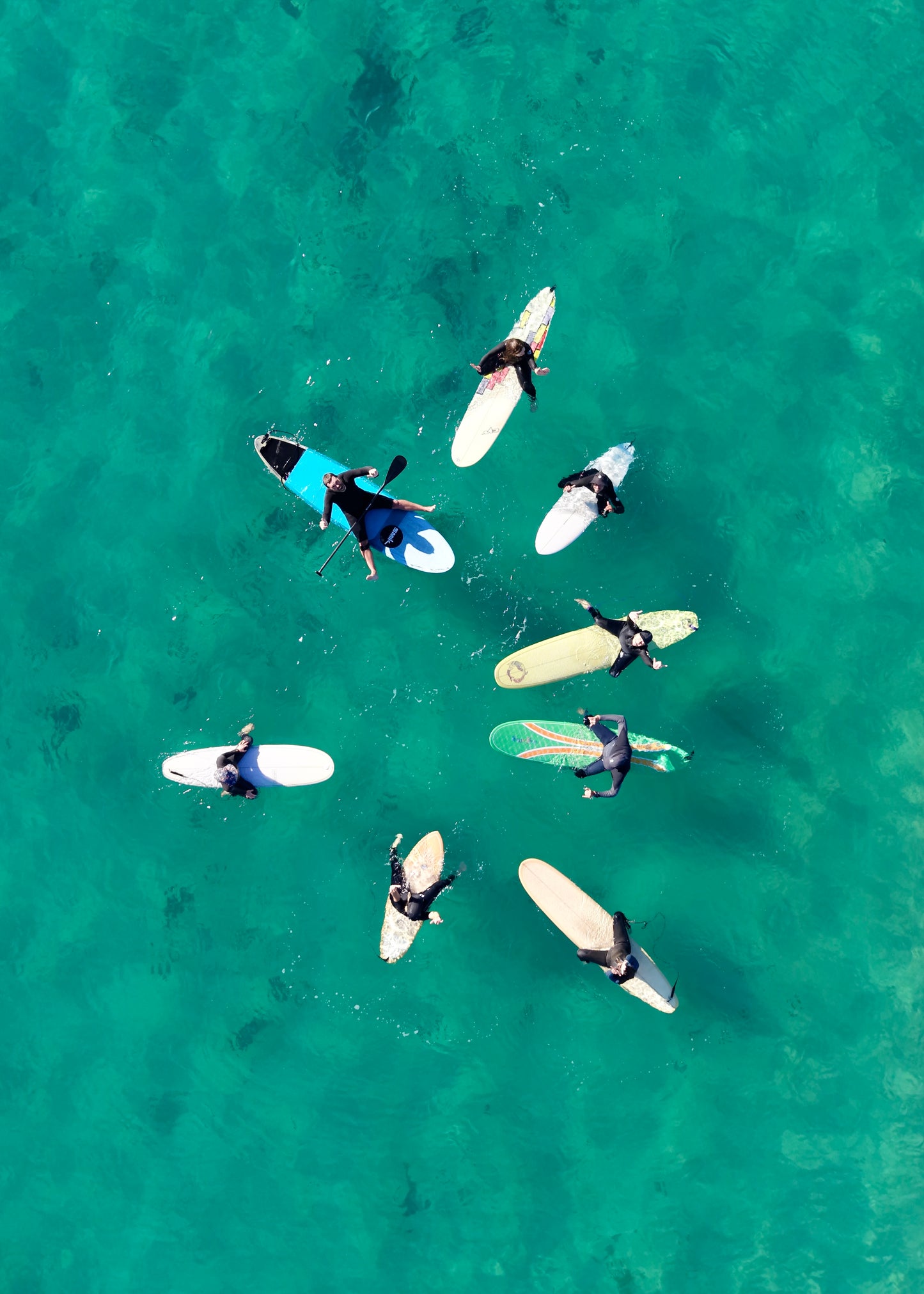 A group of surfers on their surfboards in clear green  water at Gunnamatta surf beach