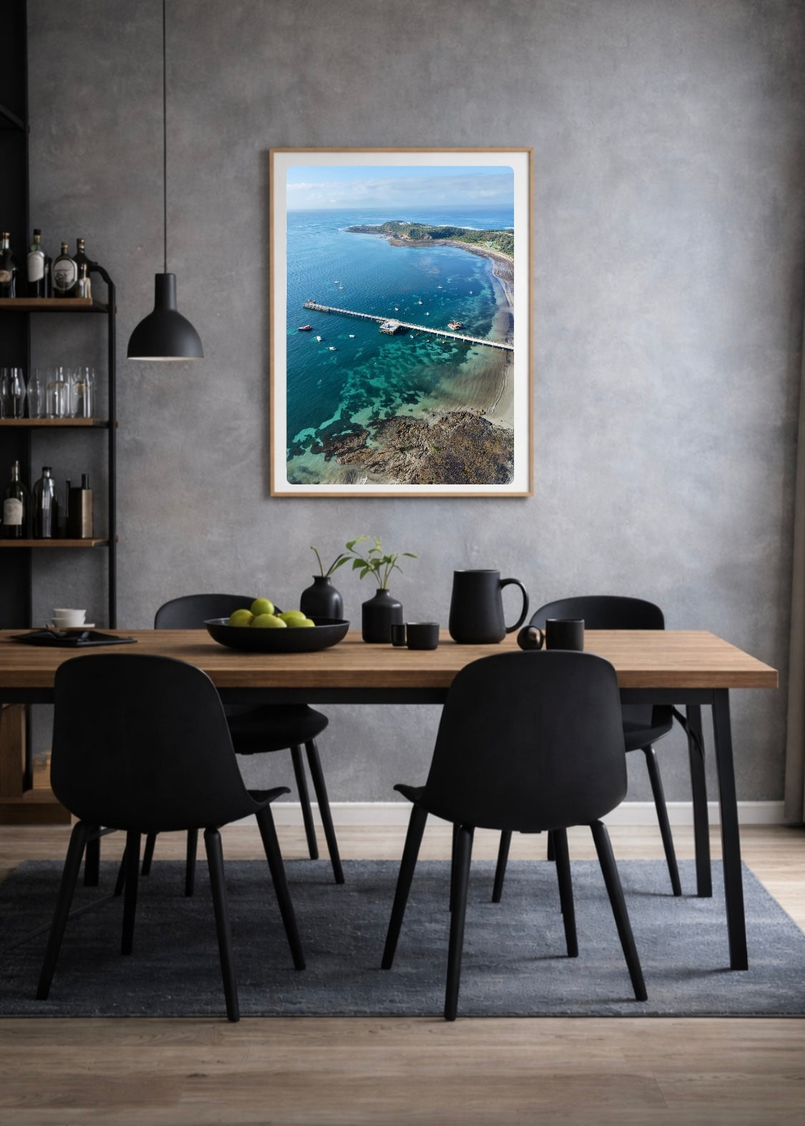 Dining room with a wooden table and black chairs, featuring a large framed picture Flinders Pier and the bay on the wall.