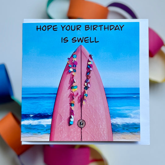 greeting card with a pink surfboard with the surf beach in the background