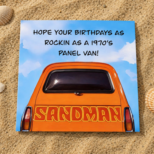 A square printed card  placed on sand, featuring an orange vintage panel van with the word 'SANDMAN' on the back and the text 'HOPE YOUR BIRTHDAYS AS ROCKIN AS A 1970'S PANEL VAN!' against a blue sky background.