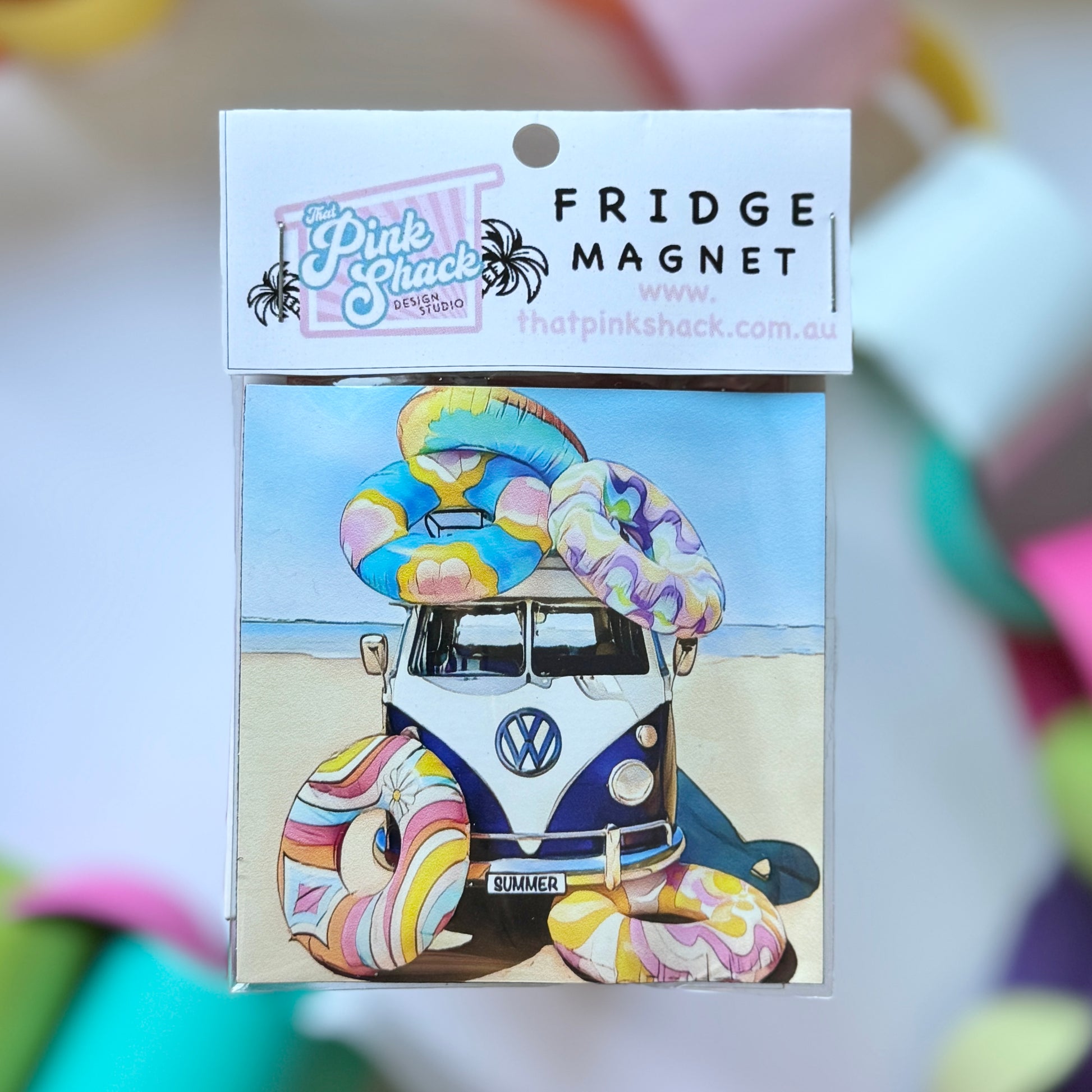 A fridge magnet with a kombi vw bus on the beach covered in inflatable blowup rings in packaging