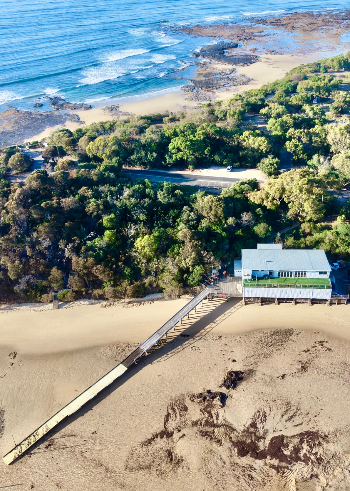 Drone print of the point Leo  boat club at low tide with surf lines in the background of the surf beach 