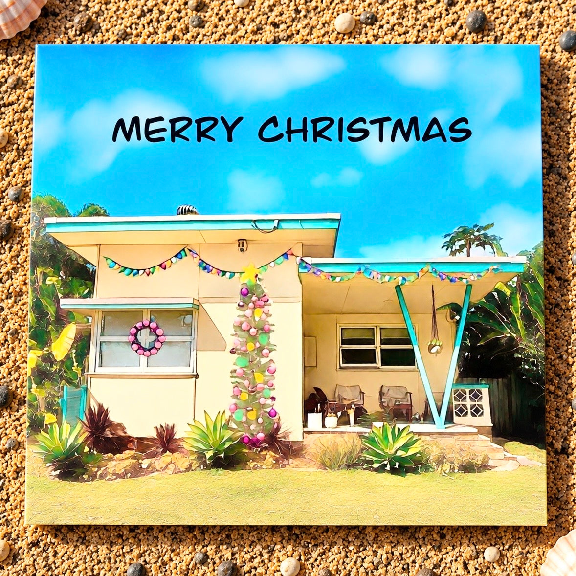 A primed quare Christmas greeting card featuring a vintage yellow beach shack with Christmas tree and a pink wreath on the window 