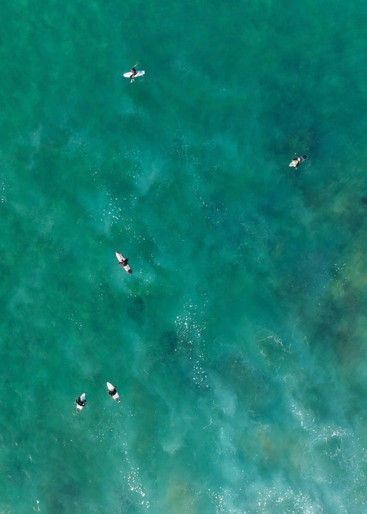A group of surfers in the moody ocean from an aerial perspective