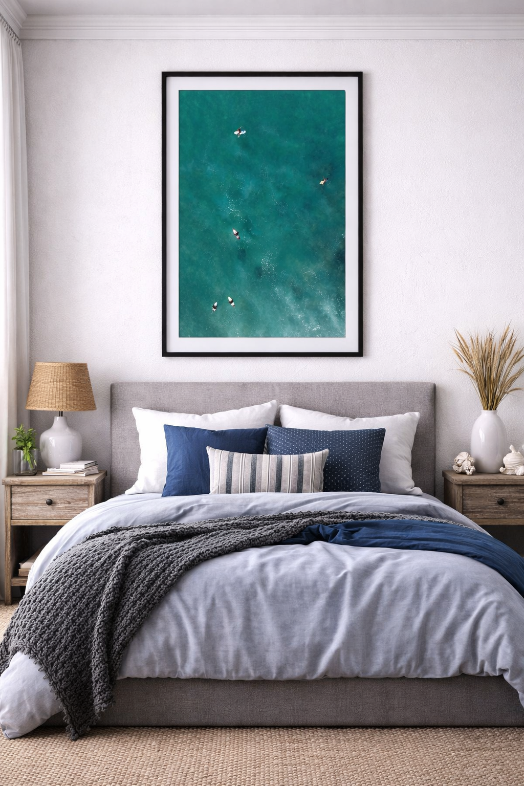 Bedroom with a large bed, nightstands, and a framed picture of A group of surfers in the moody ocean from an aerial perspective