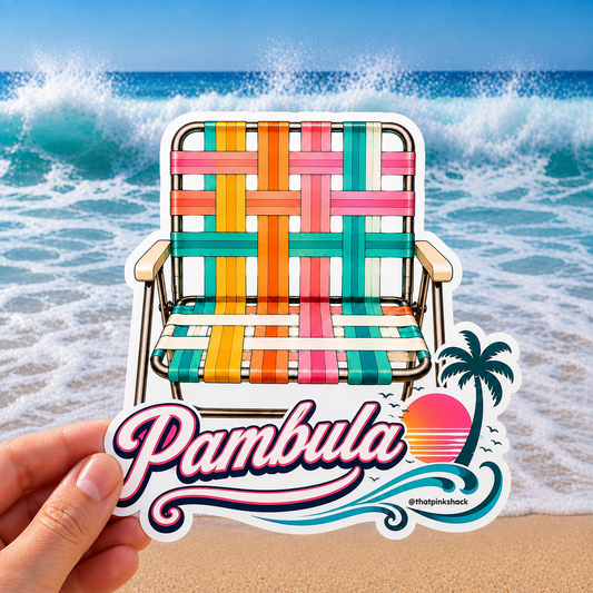 A hand holds a die-cut sticker featuring a colorful woven retro beach chair in front of a beach scene with ocean waves and sand. The sticker includes the text 'Pambula' in large pink script, a palm tree, a sunset