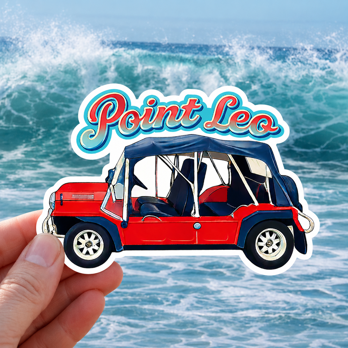 A hand holds a die-cut sticker featuring a red and navy convertible dune buggy with the text 'Point Leo' above it, set against a background of ocean waves.