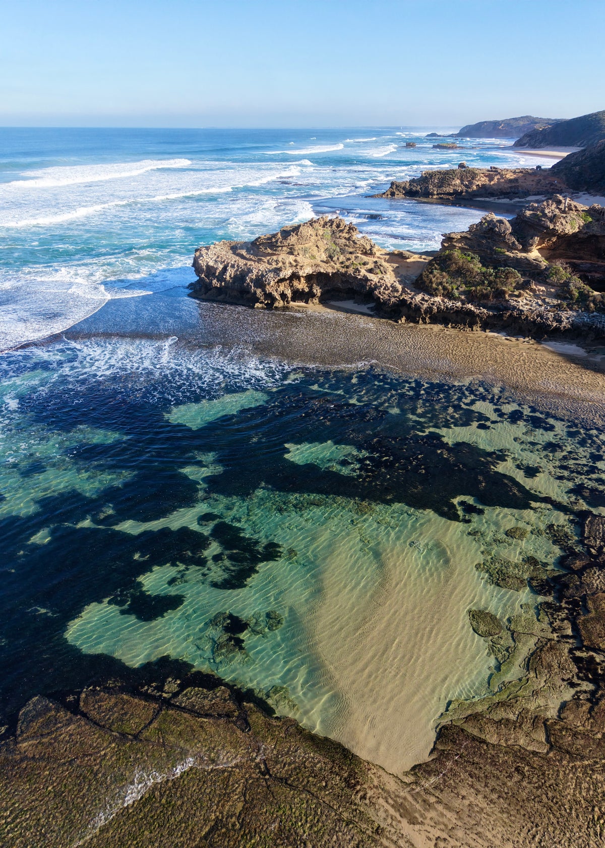 Aerial coastal photograph of rock pools, rugged coastline and ocean waves at Portsea Back Beach on the Mornington Peninsula, Victoria.