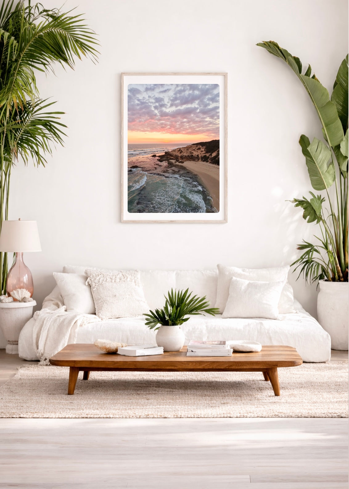 Modern living room with a white sofa, wooden coffee table, and a framed print of Sorrento Beach at Sunset on the wall.