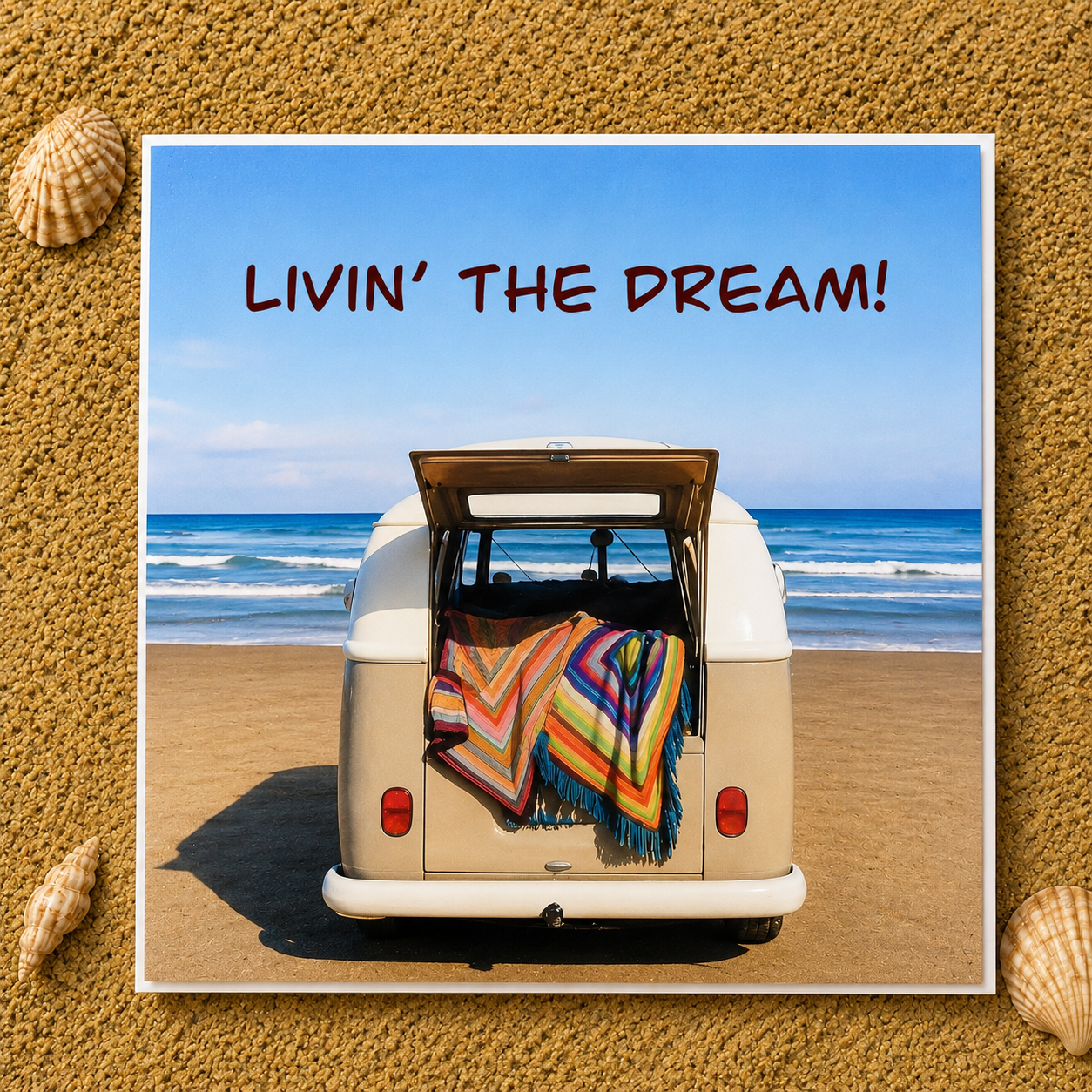 Share greeting card reading 'LIVIN’ THE DREAM!' above a retro cream van parked on a beach with the ocean and blue sky behind it. The cover is centered on a sand textured background with decorative seashells in the corners.