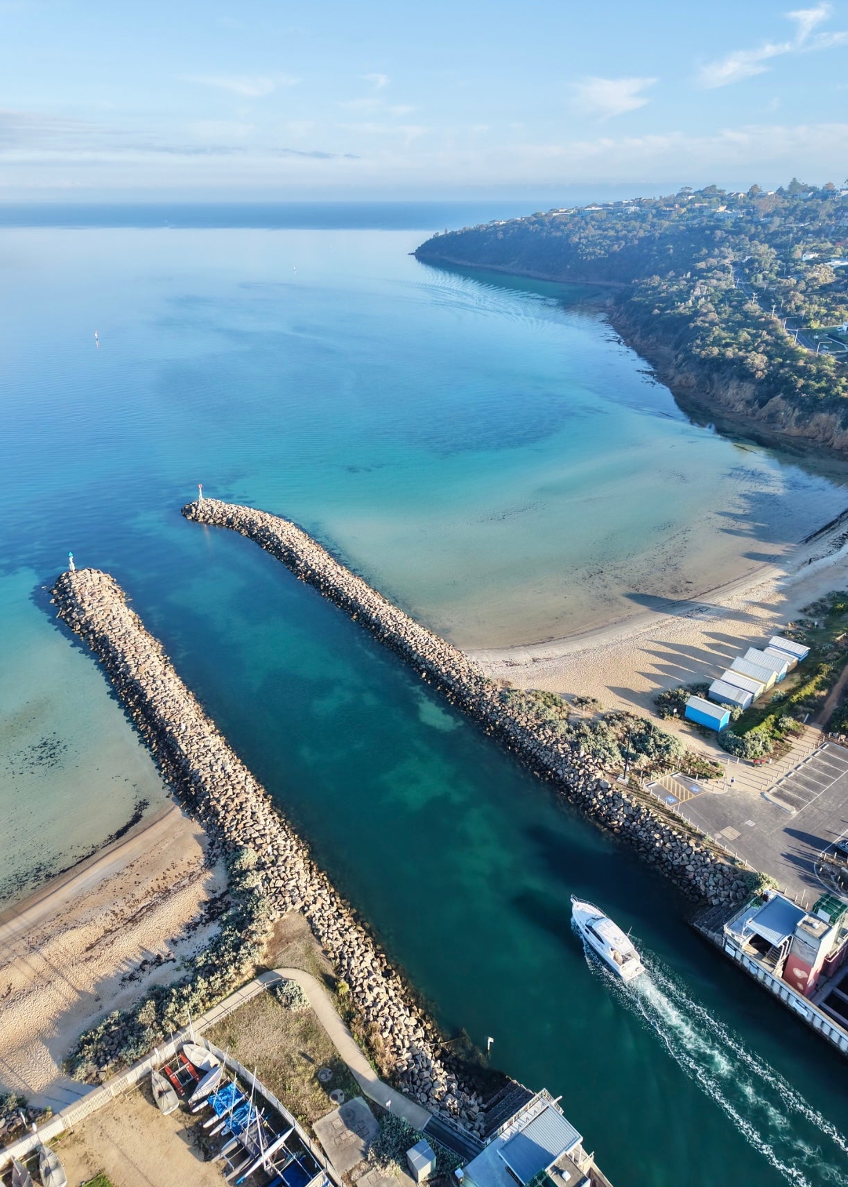 Aerial drone print of the breakwater at Martha Cove and Tassells cove Safety Beach with a boat gliding  through the water