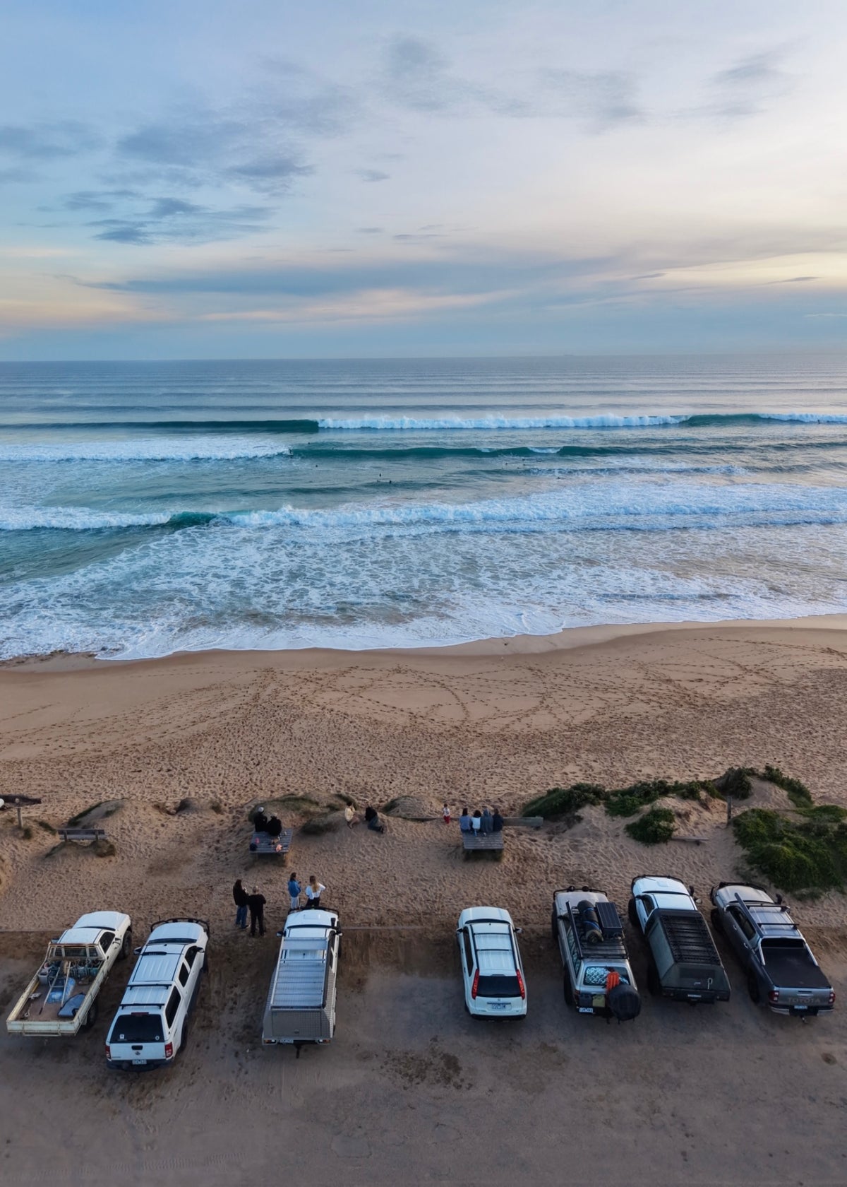 The surf lineup at rye car park with a bunch of cars lined up and people watching the sets roll in 
