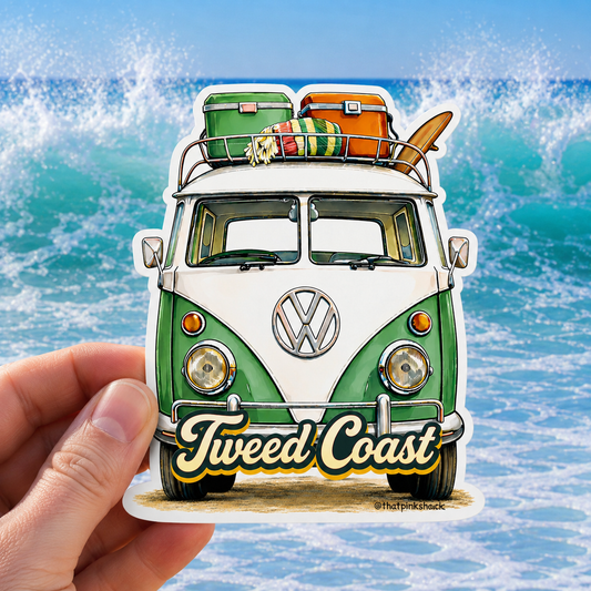 A hand holds a die-cut sticker featuring a retro green and white Volkswagen camper van with surf gear on top and the words 'Tweed Coast' on the front, set against a beach wave background.